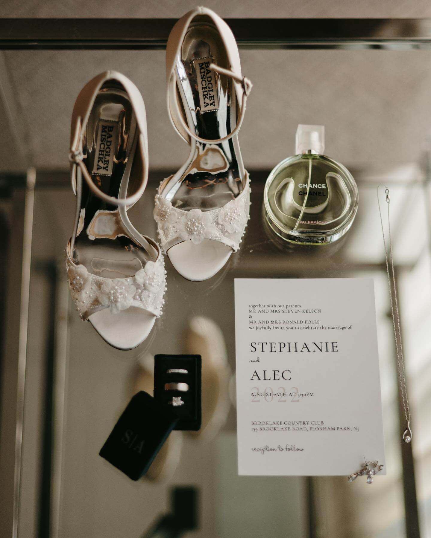 A pair of wedding shoes and a wedding invitation are elegantly displayed on a table at one of the premier outdoor wedding venues in NJ, Florham Park.